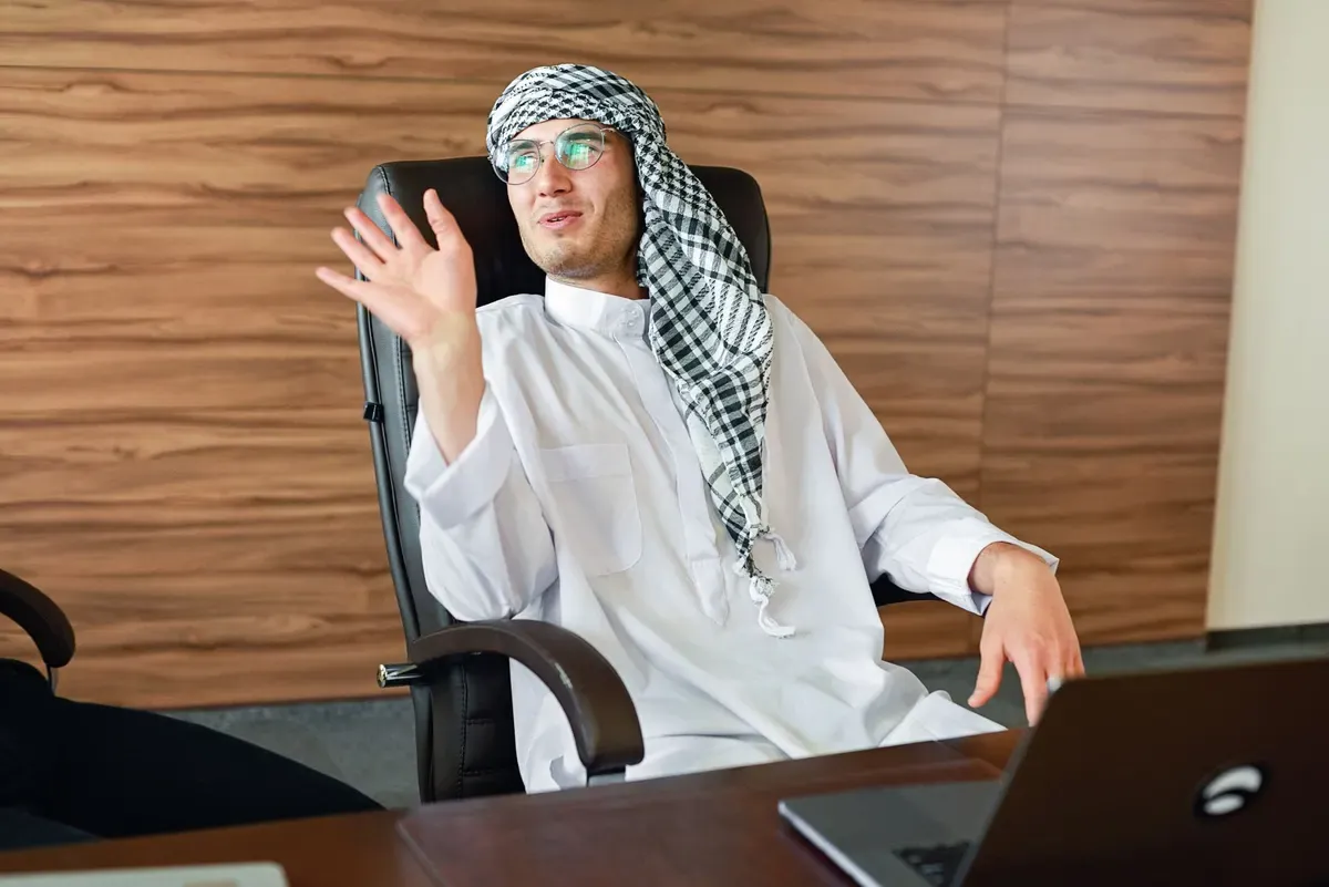 رجل بزي خليجي يتحدث أمام حاسوبه المحمول في مكتب