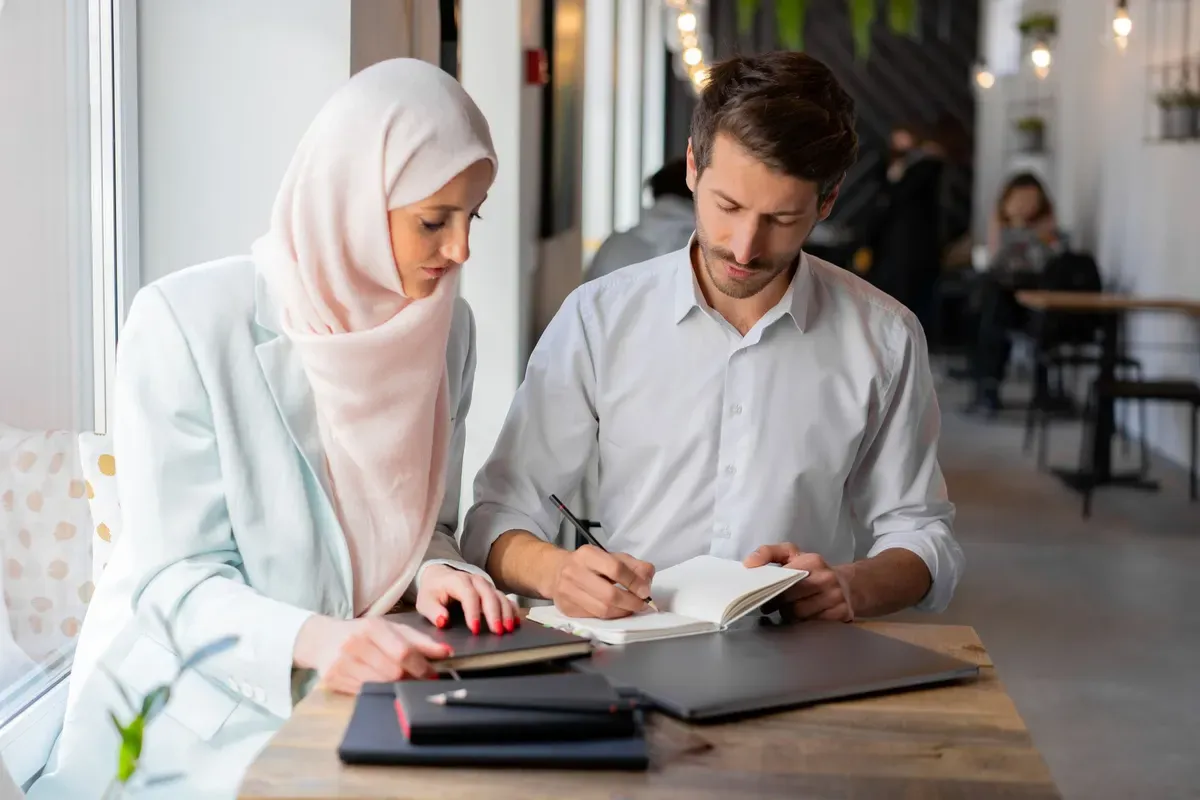 زميلان يتعاونان على حاسوب محمول في مكتب حديث
